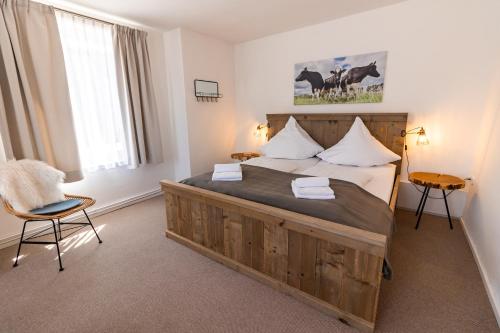 a bedroom with a large wooden bed and a chair at Alte Bäckerei Hamswehrum in Krummhörn