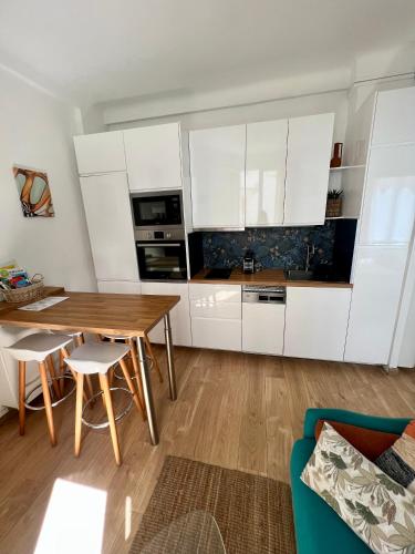 une cuisine avec des armoires blanches et une table en bois dans l'établissement T2 centre ville de Nice face de la gare routière Nice ville, à Nice