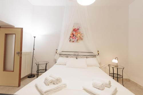 a bedroom with a white bed with a painting on the wall at Trullo La Dolce Kuki in La Correggia