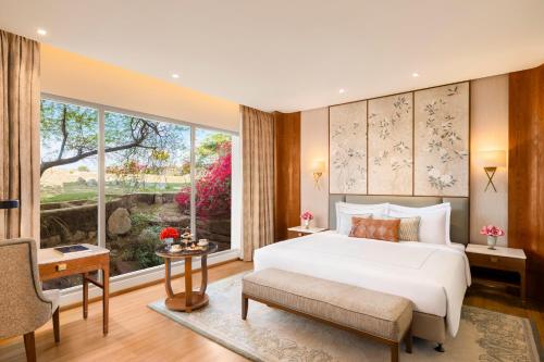a bedroom with a large bed and a large window at Taj Surajkund Resort & Spa, Delhi NCR in Faridabad