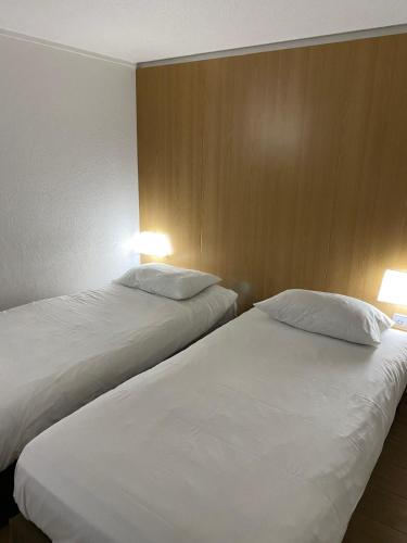 deux lits côte à côte dans une pièce dans l'établissement Kyriad ECO - Belfort Bessoncourt, à Belfort