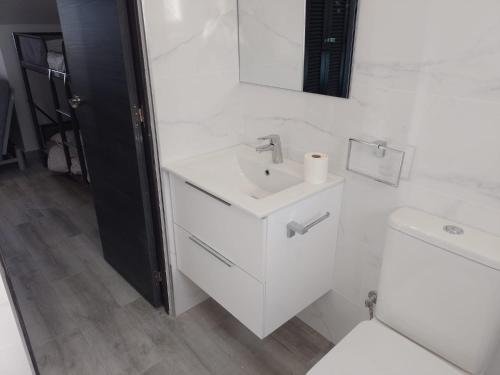 a white bathroom with a sink and a toilet at El Mirador, Villamartin, Refurbished,cot to hire, WIFI, pool, parking in Villamartin