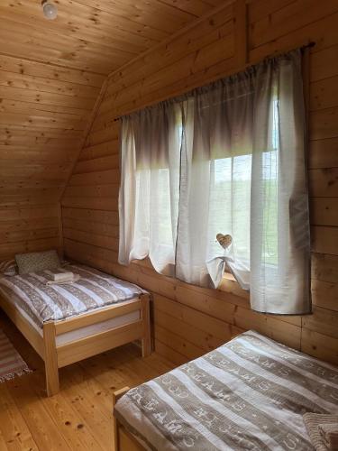 two beds in a log cabin with a window at Resort Dudukovic 2 in Slunj