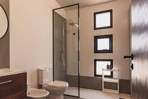 a bathroom with a toilet and a glass shower at La Casa de Cristal by Puerto Dijama in Carmelo