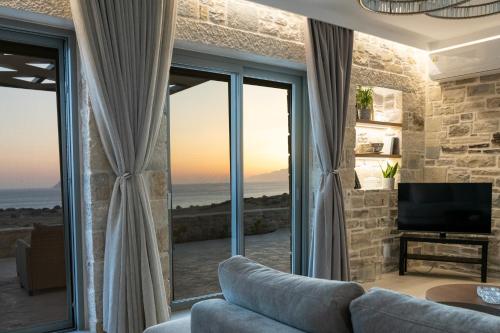 ein Wohnzimmer mit Couch und großem Fenster in der Unterkunft Villa Sofita Komos View in Pitsidia