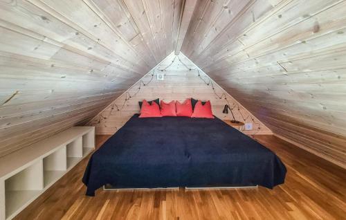 a bed in a wooden room with red pillows at Nice Apartment In Auklandshamn in Vestvik
