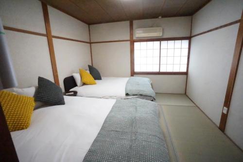 a small room with two beds and a window at Family Home Osaka Kujo Guest House in Osaka