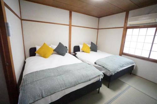 two beds in a room with two windows at Family Home Osaka Kujo Guest House in Osaka