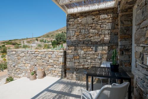 a patio with a table and a stone wall at Noble 7 Suites - Adults Only - Onar Hotels Collection in Parikia