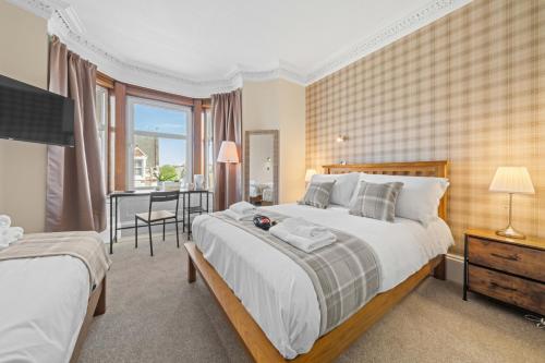 Un dormitorio con una cama grande y un escritorio. en mySTAYINN Cedar Villa Guest House, en Inverness