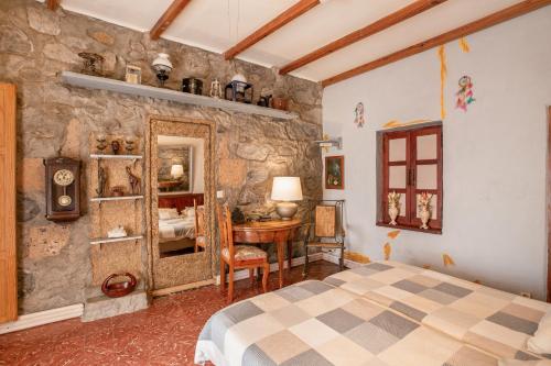 a bedroom with a stone wall with a bed and a desk at Casa Rustica San Francisco 3 in Telde
