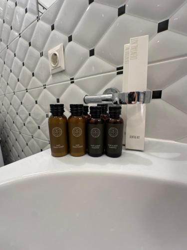 three bottles of honey sitting on a counter in a bathroom at Heart of Saint Peter Apartments in Rīga