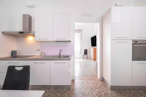 a kitchen with white cabinets and a black chair at Biancolino Apartments in Nardò