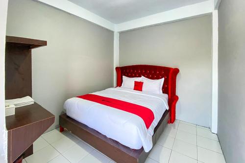 a bed with a red headboard in a room at RedDoorz at Graha Aisyah Setiabudi Medan in Sunggal