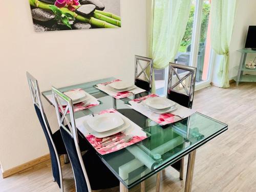 a glass table with chairs and plates on it at H N H Ferienwohnung in Lindau