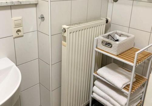 a bathroom with a radiator and towels on a shelf at H N H Ferienwohnung in Lindau