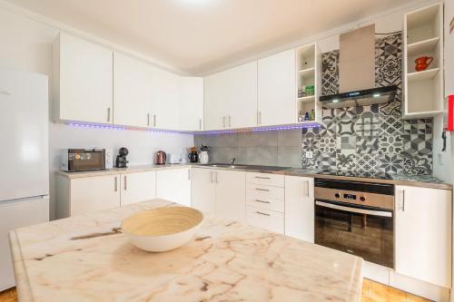 a kitchen with white cabinets and a bowl on a counter at GuestReady - Serene Escape Close to Aroeira Beach in Charneca