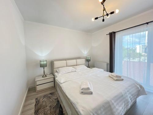 a white bedroom with a large bed and a window at Cozy North 35 in Cluj-Napoca