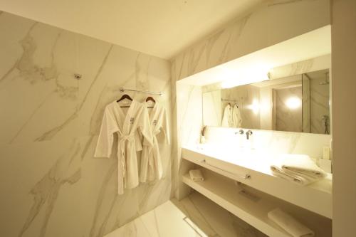 a white bathroom with a sink and a mirror at Azur Hotel in Athens