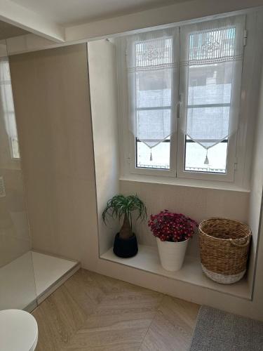 une salle de bains avec deux plantes en pot sur un rebord de fenêtre dans l'établissement Gaya, à Nice