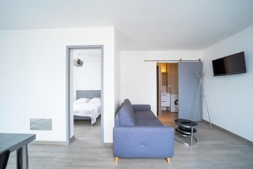 un salon avec un canapé bleu et une chambre dans l'établissement Villa Welcom 3 - 3min à Pied de la Plage, à Canet