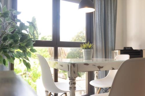 a table with white chairs in front of a window at La Antigua Fonda in Hervás