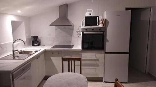La cuisine blanche est équipée d'un réfrigérateur et d'un évier. dans l'établissement Campagne et mer, à Saujon