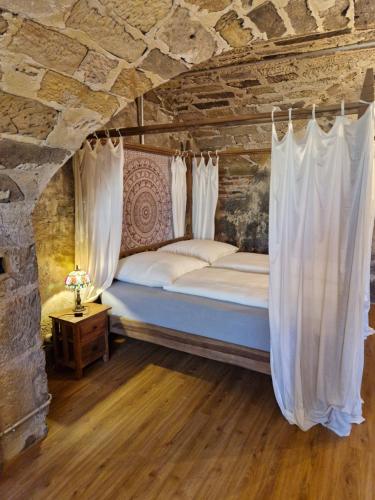 un lit avec des rideaux blancs dans une pièce avec un mur en pierre dans l'établissement Schlossgut Franken - Schlossapartment Iring, à Redwitz an der Rodach