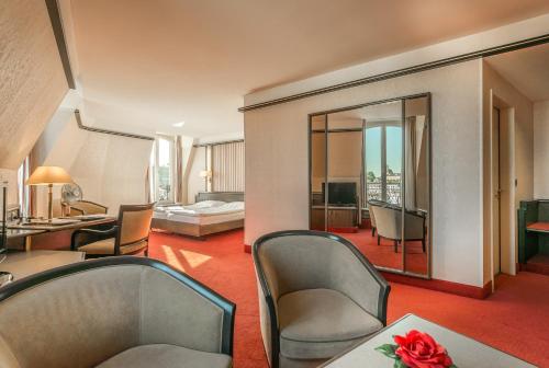 um quarto de hotel com um quarto e uma sala de estar em Hotel Monopol Luzern em Lucerna