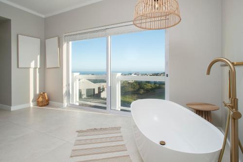 a white bathroom with a tub and a large window at Vermont Vista - With Pool in Hermanus