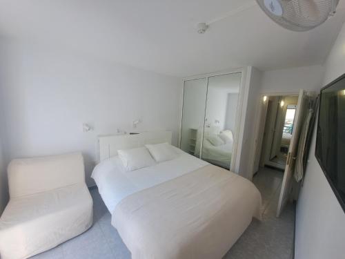 a white bedroom with a white bed and a mirror at BEACHITO Puerto Naos in Puerto Naos
