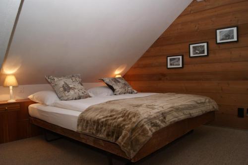 ein Schlafzimmer mit einem Bett mit einer Holzwand in der Unterkunft Hotel Arturo in Celerina