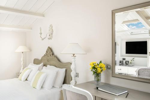 a bedroom with a bed with a desk and a mirror at Micra Anglia Boutique Hotel & Spa in Andros