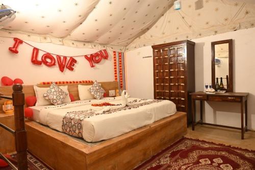 1 dormitorio con 1 cama con una señal de amor en la pared en Ishav Guest House Jsm, en Jaisalmer