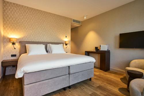 a hotel room with a bed and a flat screen tv at Eilandhotel Texel - Nieuw geopend hotel in De Cocksdorp