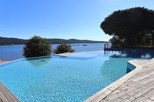 une grande piscine à côté d'un corps d'eau dans l'établissement T2 cabine avec vue mer, accès plage & piscine, à Pianottoli-Caldarello