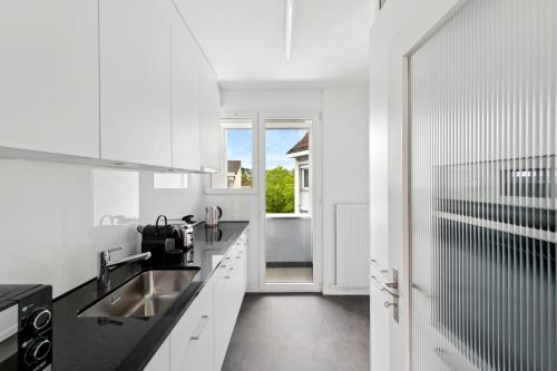 a white kitchen with a sink and a window at The R Apartment Hagen in Schaffhausen