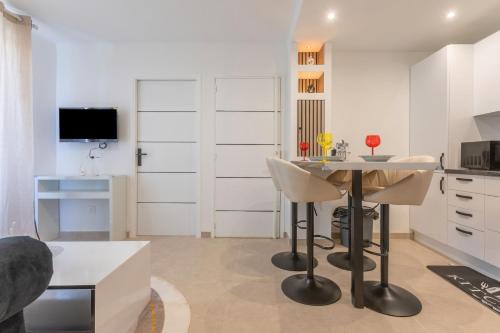 une cuisine avec des armoires blanches et une table et des chaises dans l'établissement Appartement 113, à Cogolin