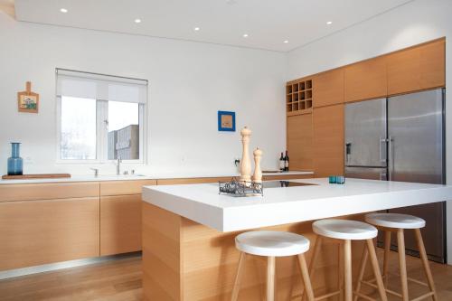 a kitchen with a large white counter and stools at The Golden Circle Lodge - Luxurious villa with Sauna in Þingvellir