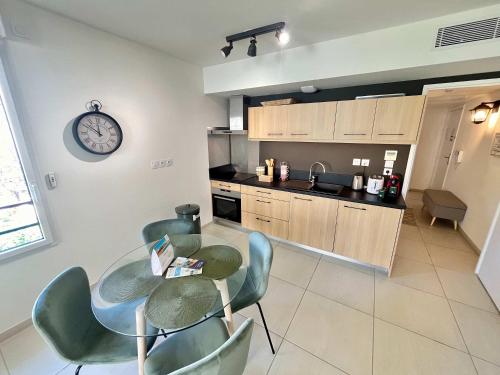 une cuisine avec une table et des chaises et une horloge au mur dans l'établissement B035 Magnifique appartement neuf a deux pas du centre, à Cannes