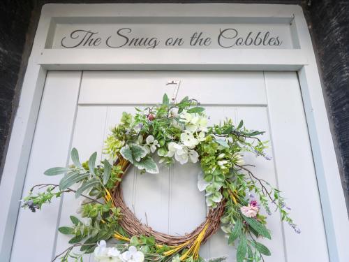 a wreath on a door with a sign on it at The Snug on the Cobbles in Keighley