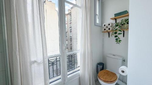 La salle de bains est pourvue de toilettes et d'une grande fenêtre. dans l'établissement Le Repaire Tranquille, à Paris