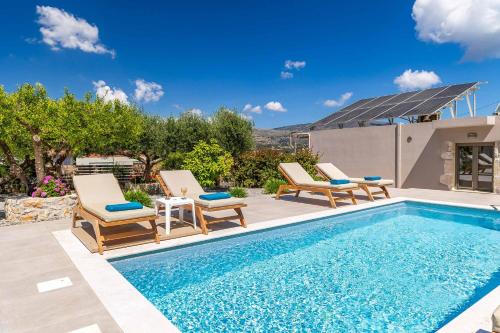 a swimming pool with two lounge chairs next to a house at Villa Eva Chania in Neo Chorio