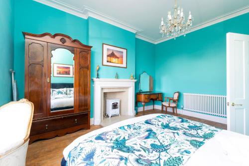 a blue bedroom with a bed and a fireplace at Luxury pair of Georgian apartments, hot tub, sea views, sleeps 12 in Bognor Regis