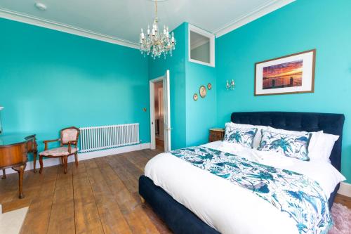 a bedroom with blue walls and a bed and a desk at Luxury pair of Georgian apartments, hot tub, sea views, sleeps 12 in Bognor Regis