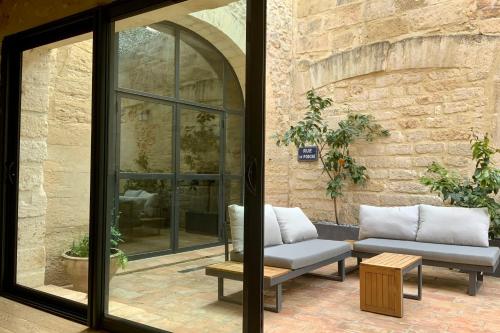 a patio with two chairs and a couch in front of a building at La Maison de la Place - Charming house with swimming pool & exposed stone in Mudaison