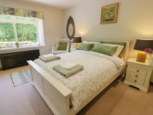 een slaapkamer met een bed, een spiegel en een raam bij Nithbank Cottage in Thornhill