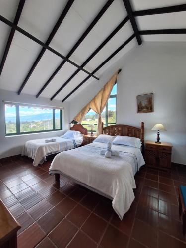 Un dormitorio con dos camas y una gran ventana. en Finca el belvedere, en Villa de Leyva