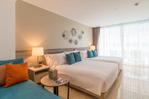 a hotel room with two beds and a couch at Centara Ao Nang Beach Resort & Spa Krabi in Ao Nang Beach
