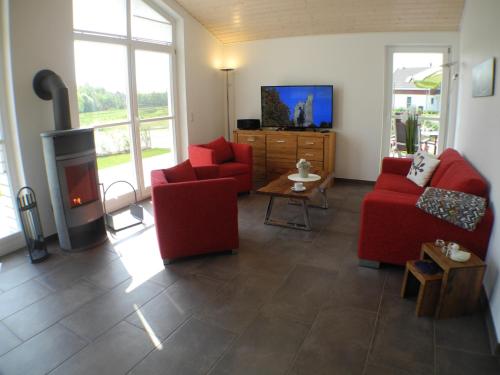 a living room with two red chairs and a fireplace at Vechteblick - Nordhorn in Nordhorn